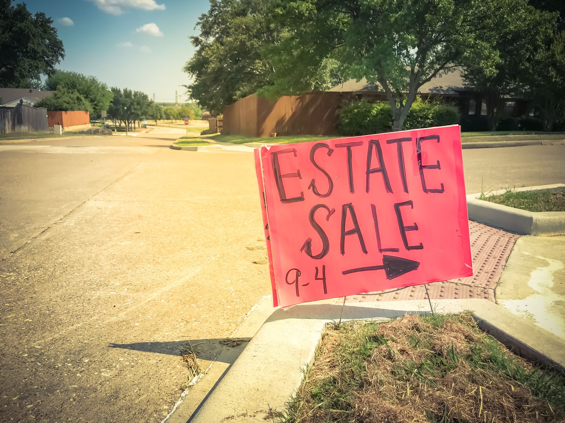 Close-up red estate sale sign with 9AM to 4PM timeframe at suburban neighborhood near Dallas
